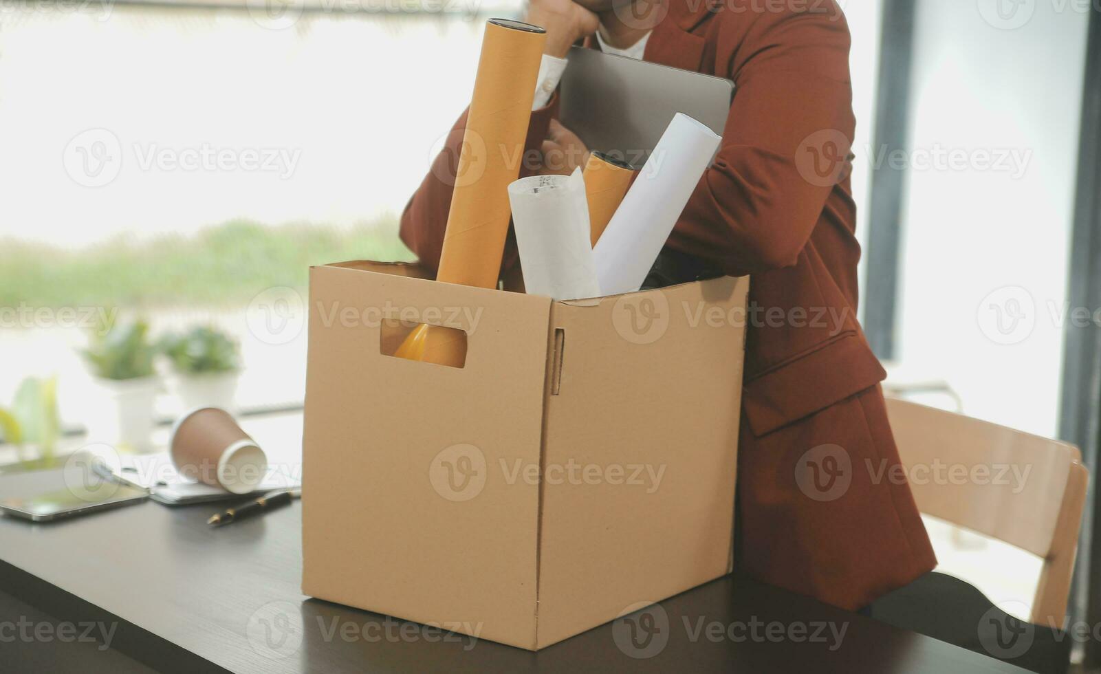 Business man employee stressful resignation from job while picking up personal belongings into brown cardboard box and carrying to walking out from office photo