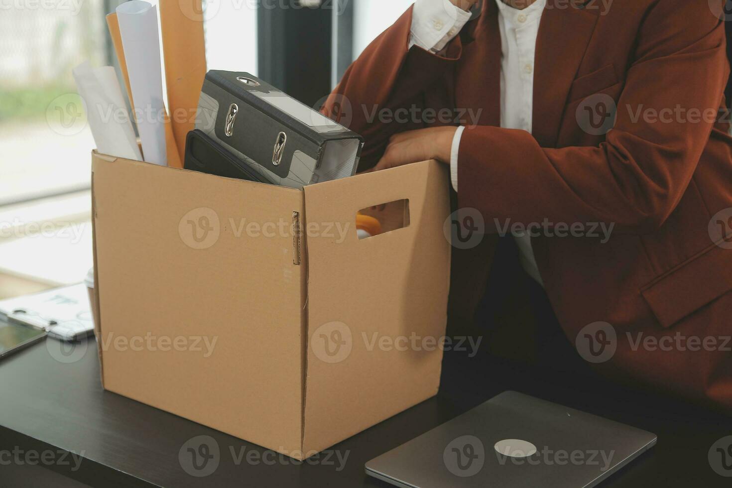 Business man employee stressful resignation from job while picking up personal belongings into brown cardboard box and carrying to walking out from office photo