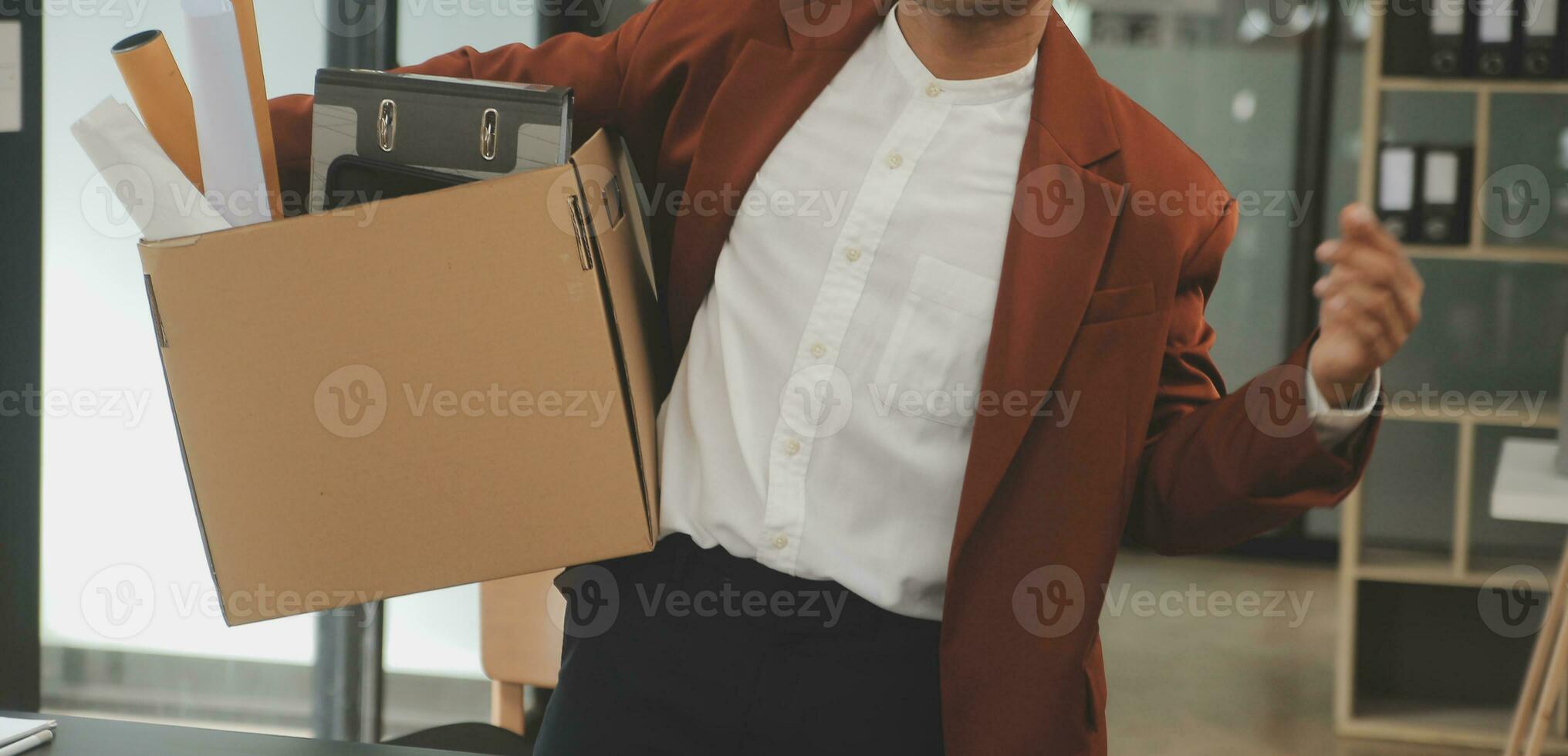 Business man employee stressful resignation from job while picking up personal belongings into brown cardboard box and carrying to walking out from office photo