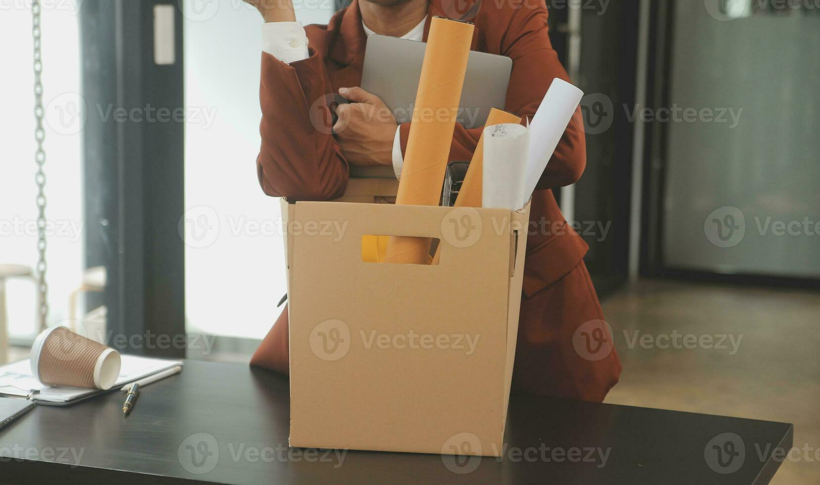 Business man employee stressful resignation from job while picking up personal belongings into brown cardboard box and carrying to walking out from office photo