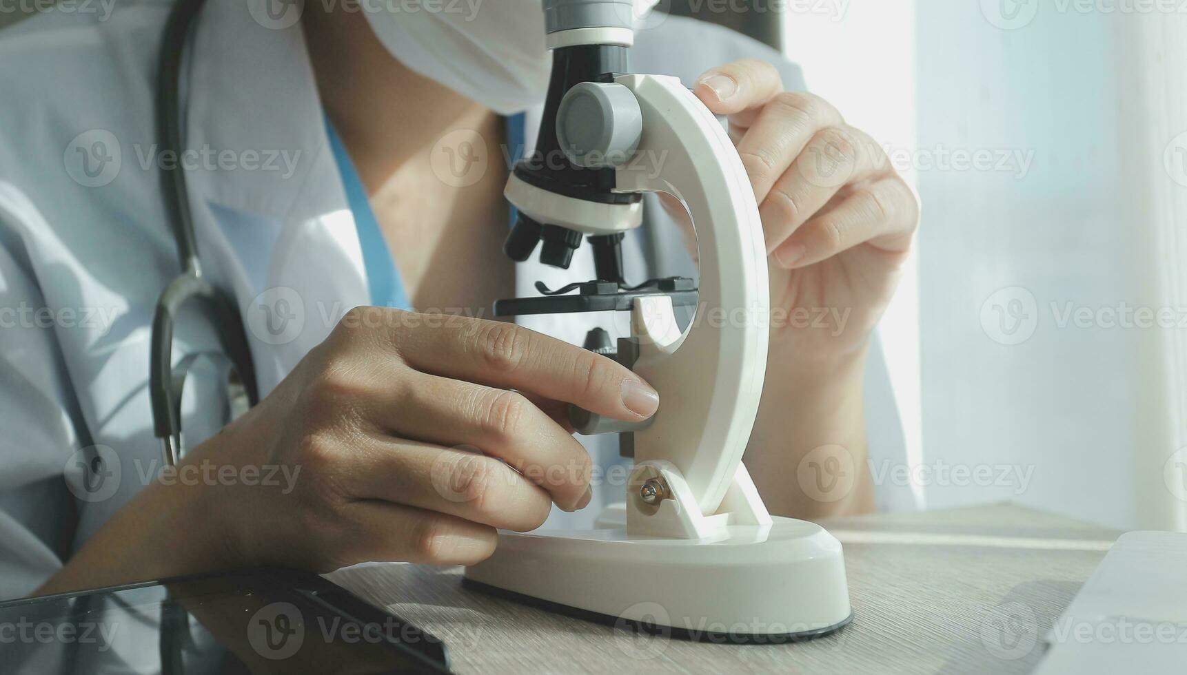 Young scientists conducting research investigations in a medical laboratory, a researcher in the foreground is using a microscope photo