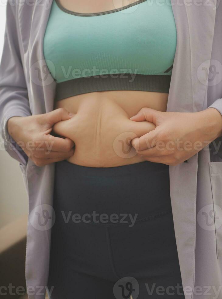 A woman shows an inflated thick belly, the concept of excess weight and weight loss photo