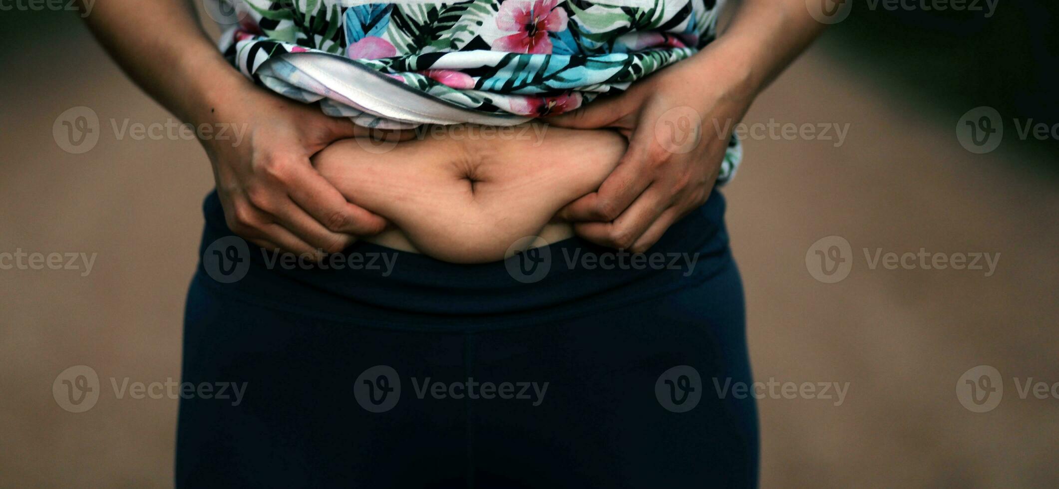 Women body fat belly. Obese woman hand holding excessive belly fat. diet lifestyle concept to reduce belly and shape up healthy stomach muscle. photo