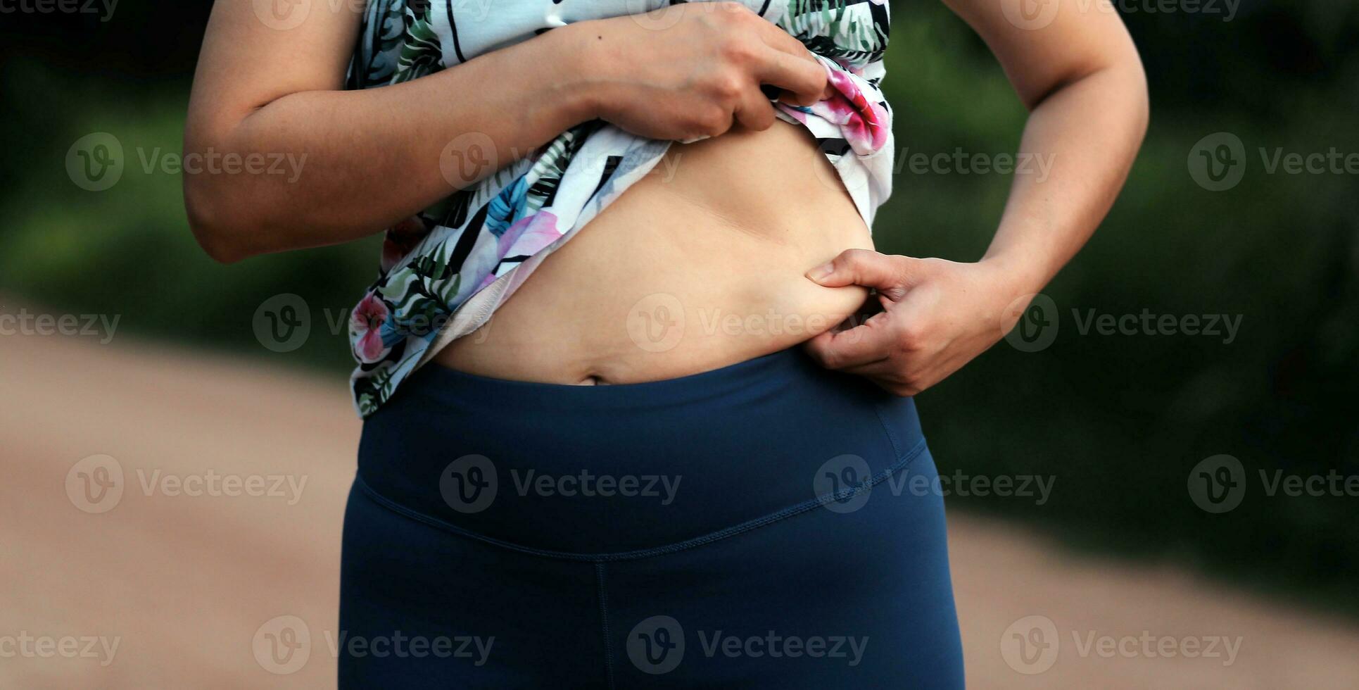 Women body fat belly. Obese woman hand holding excessive belly fat. diet lifestyle concept to reduce belly and shape up healthy stomach muscle. photo