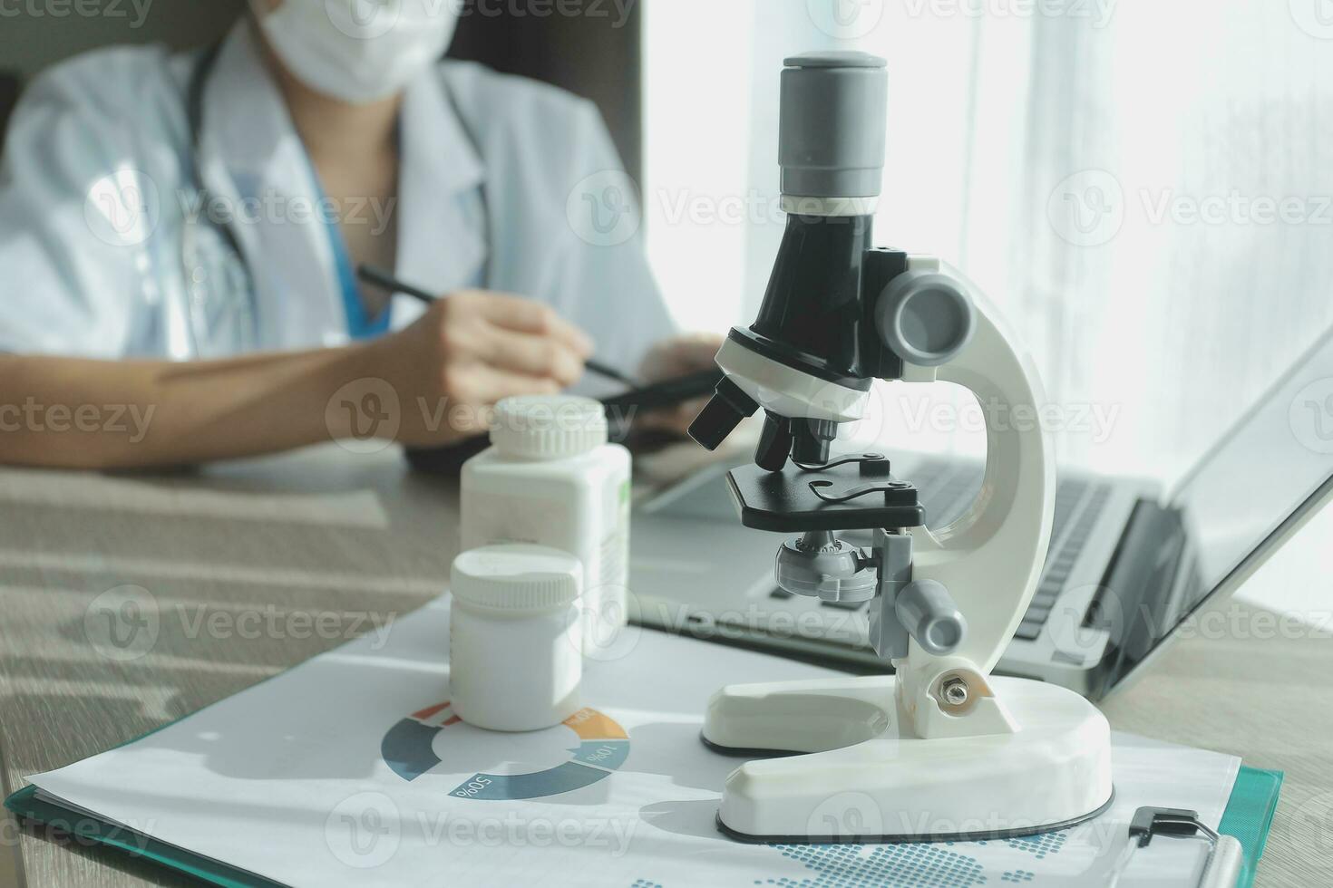 Young scientists conducting research investigations in a medical laboratory, a researcher in the foreground is using a microscope photo