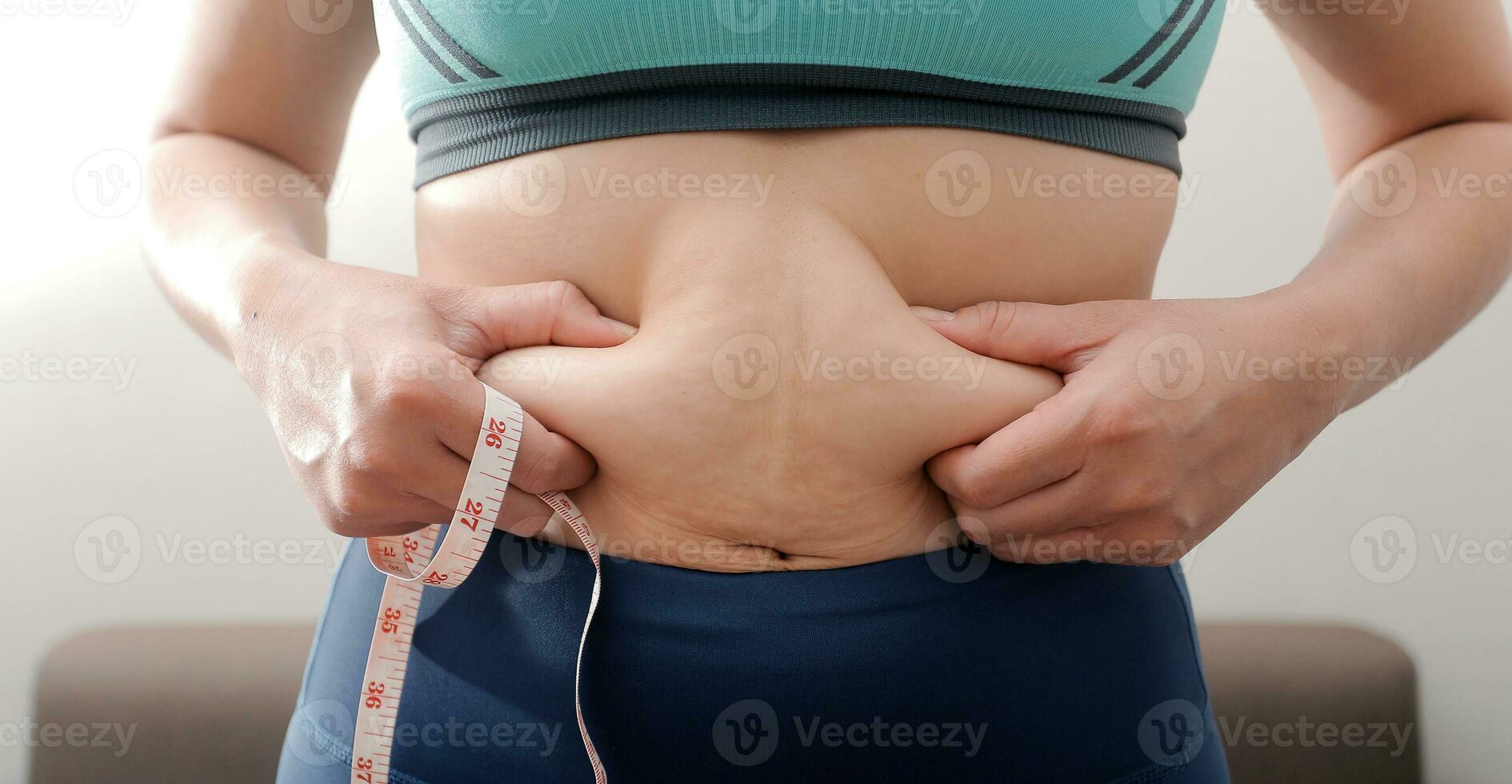 Women body fat belly. Obese woman hand holding excessive belly fat. diet lifestyle concept to reduce belly and shape up healthy stomach muscle. photo