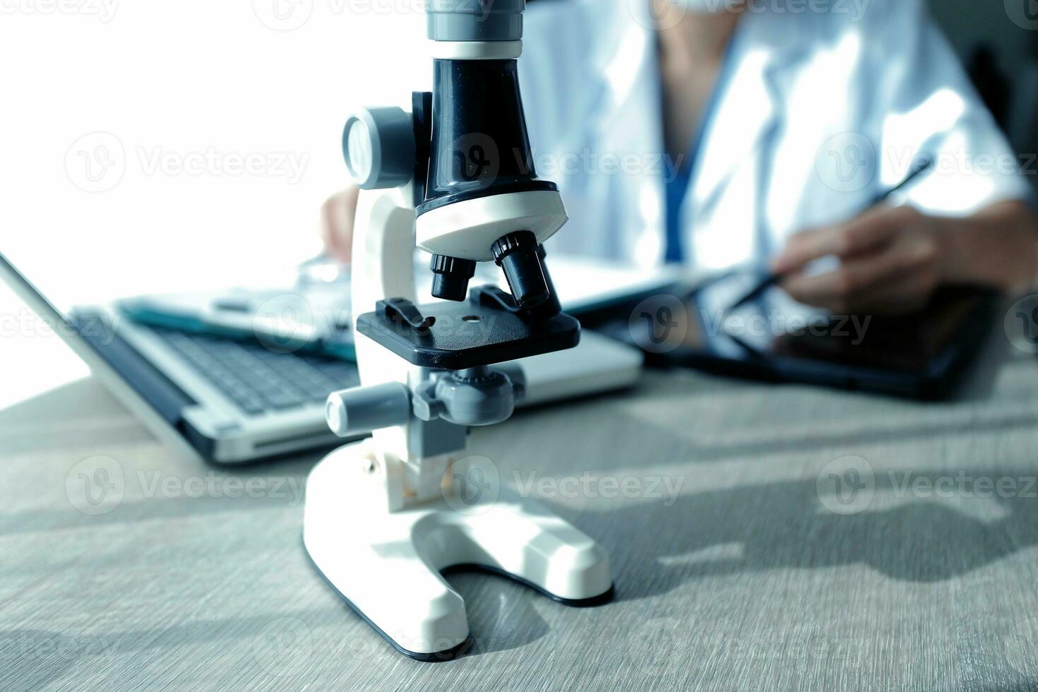 Young scientists conducting research investigations in a medical laboratory, a researcher in the foreground is using a microscope photo