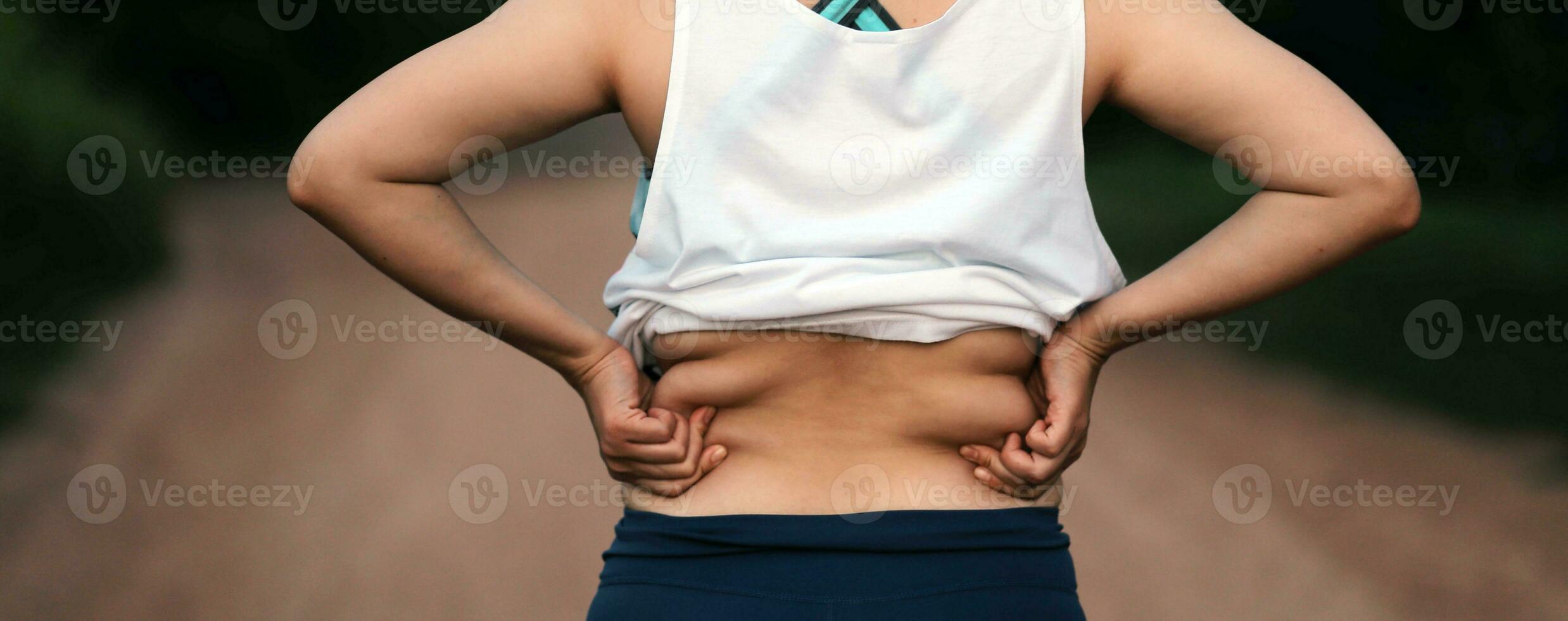 Women body fat belly. Obese woman hand holding excessive belly fat. diet lifestyle concept to reduce belly and shape up healthy stomach muscle. photo