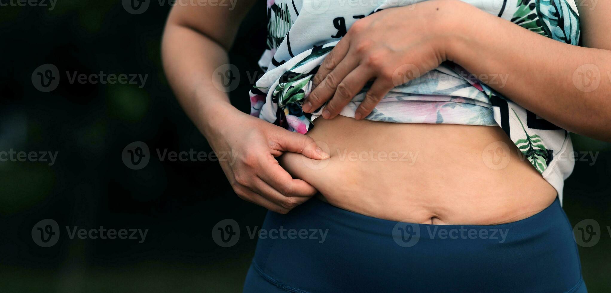 Women body fat belly. Obese woman hand holding excessive belly fat. diet lifestyle concept to reduce belly and shape up healthy stomach muscle. photo
