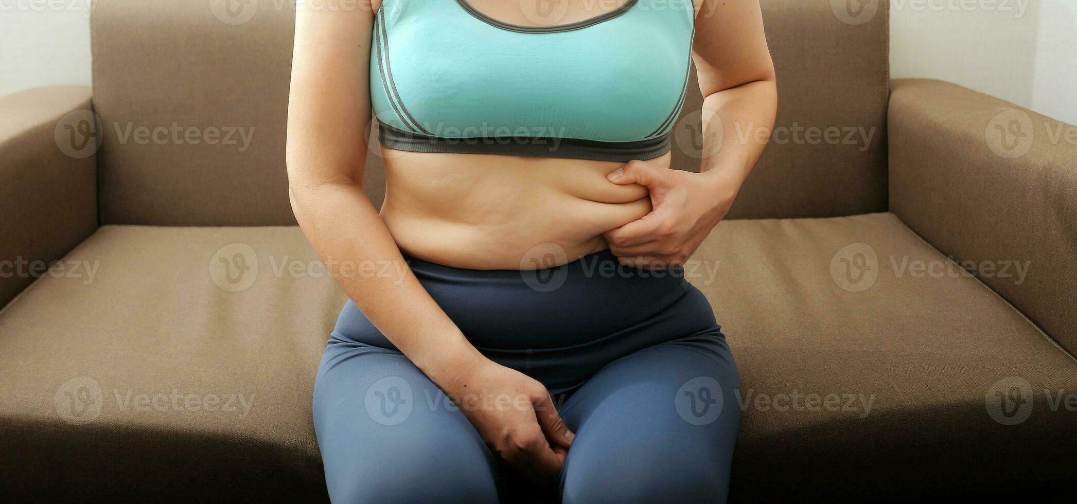Women body fat belly. Obese woman hand holding excessive belly fat. diet lifestyle concept to reduce belly and shape up healthy stomach muscle. photo
