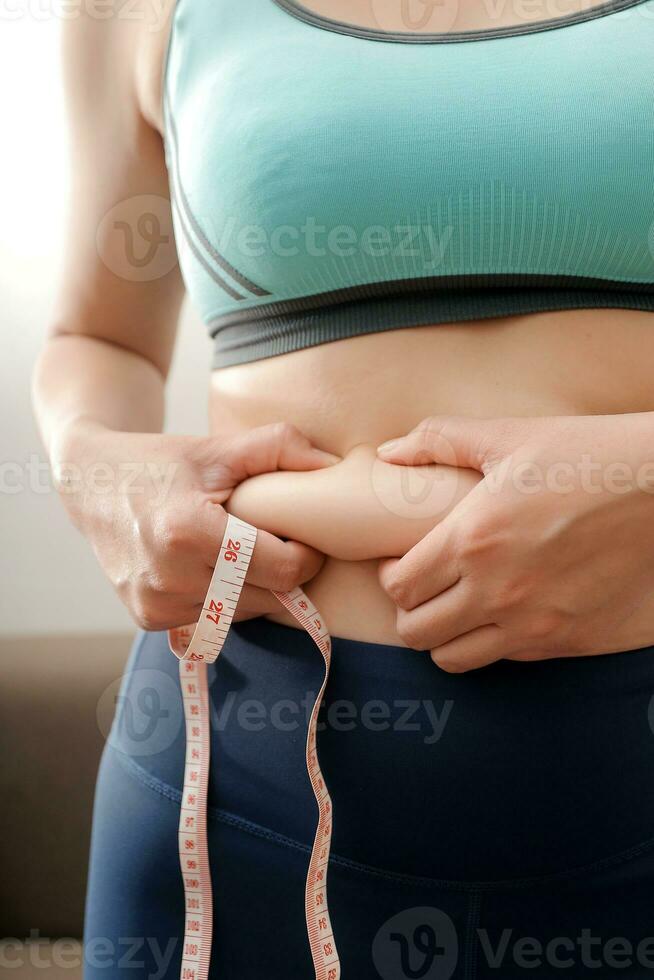 Women body fat belly. Obese woman hand holding excessive belly fat. diet lifestyle concept to reduce belly and shape up healthy stomach muscle. photo