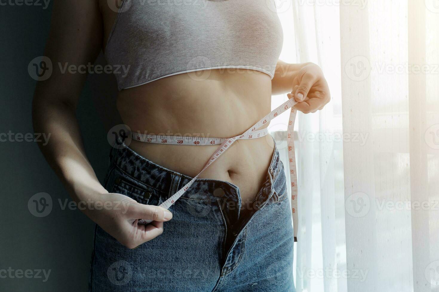 Close up of a belly with scar from c-section and abdominal fat. Women's health. A woman dressed up in sportswear demonstrating her imperfect body after a childbirth with nursery on the background. photo