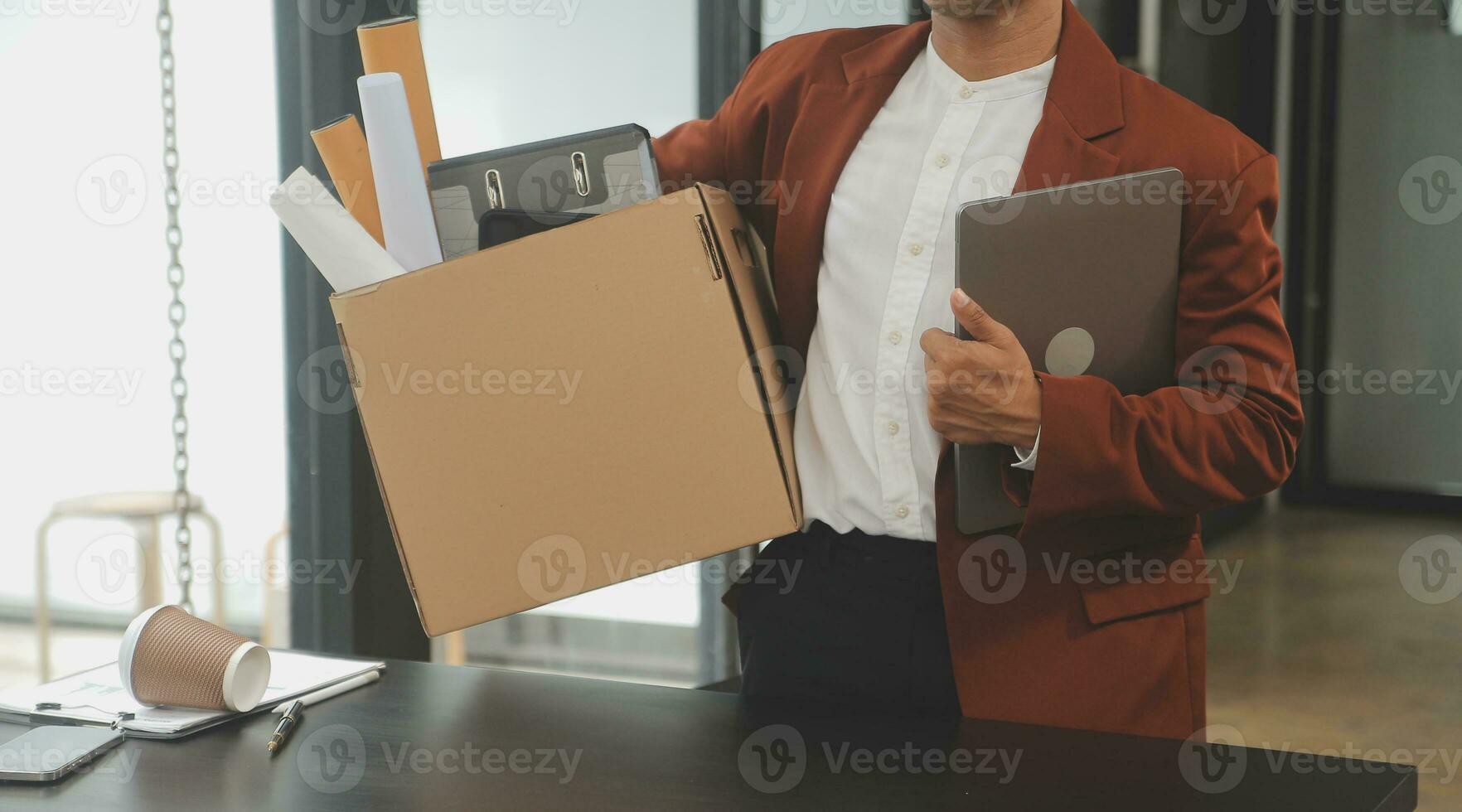 Business man employee stressful resignation from job while picking up personal belongings into brown cardboard box and carrying to walking out from office photo