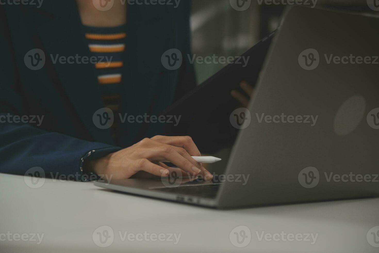 Asian Businesswoman Using laptop computer and working at office with calculator document on desk, doing planning analyzing the financial report, business plan investment, finance analysis concept. photo