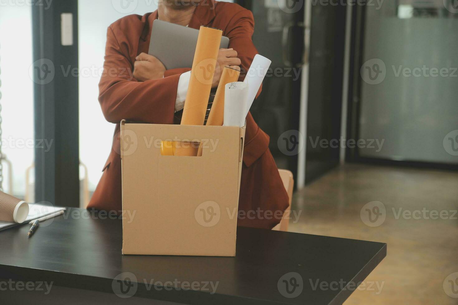 Business man employee stressful resignation from job while picking up personal belongings into brown cardboard box and carrying to walking out from office photo