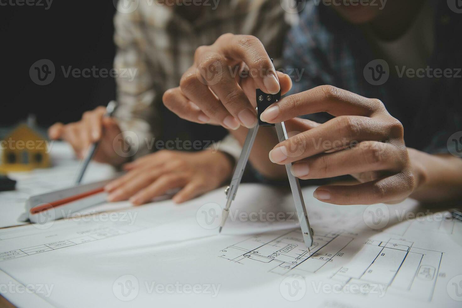 Team of multiethnic architects working on construction plans in meeting room. Engineers discussing on project in office. Mature businessman and woman standing around table working on blueprint. photo