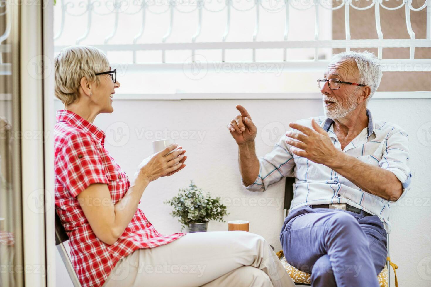 Senior couple sitting and talking on terrace at their home. Leisure time. photo