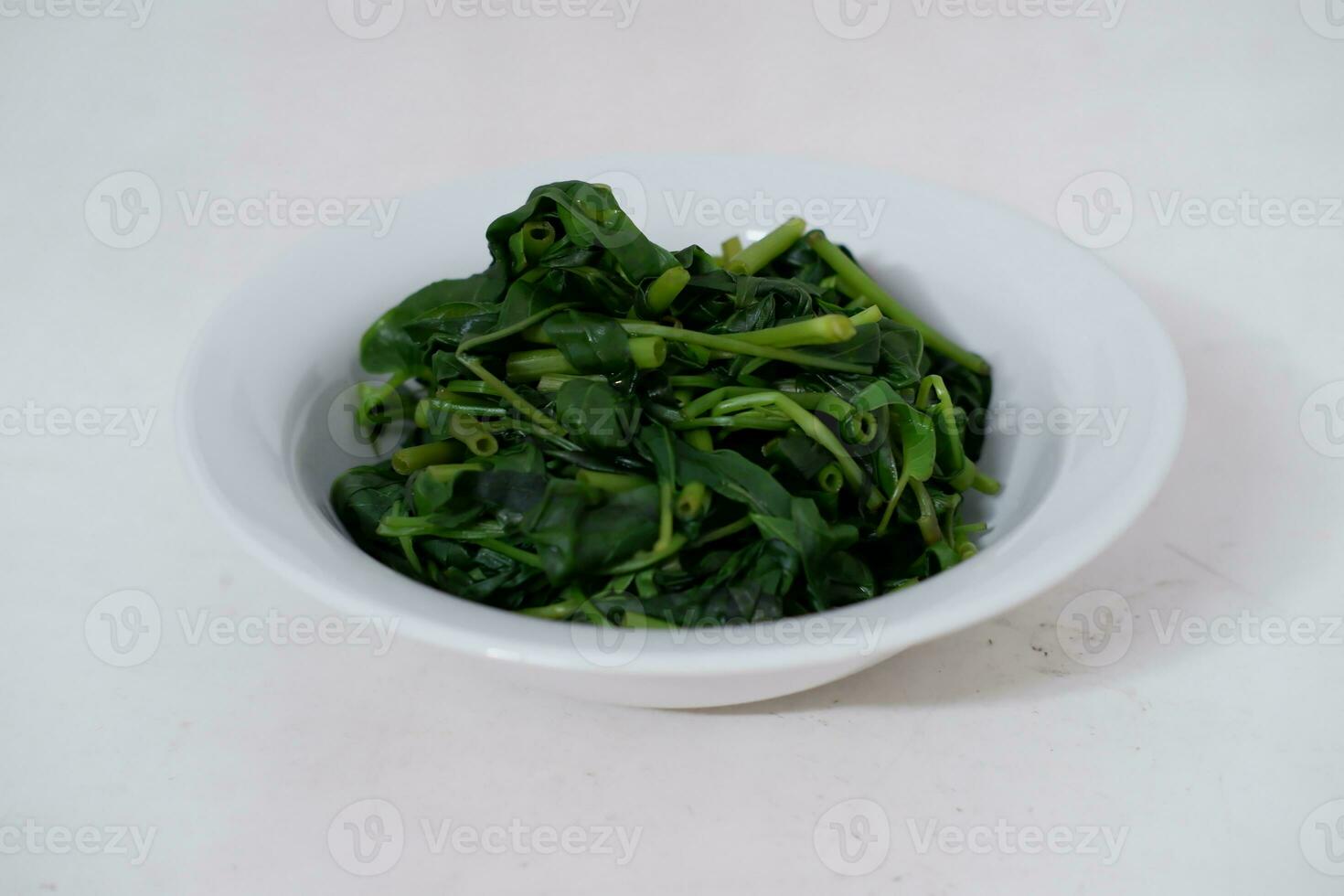Stir-fried spinach in a white bowl on a white background photo