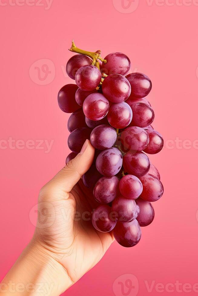 Hand holding a bunch of red grapes isolated on a red background. ai generated photo