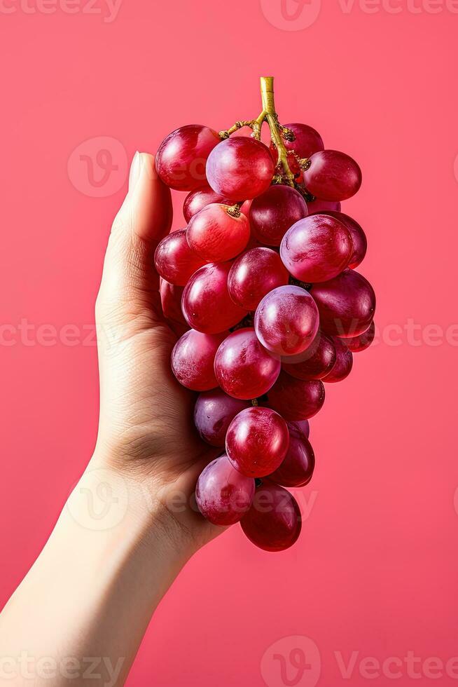 Hand holding a bunch of red grapes isolated on a red background. ai generated photo