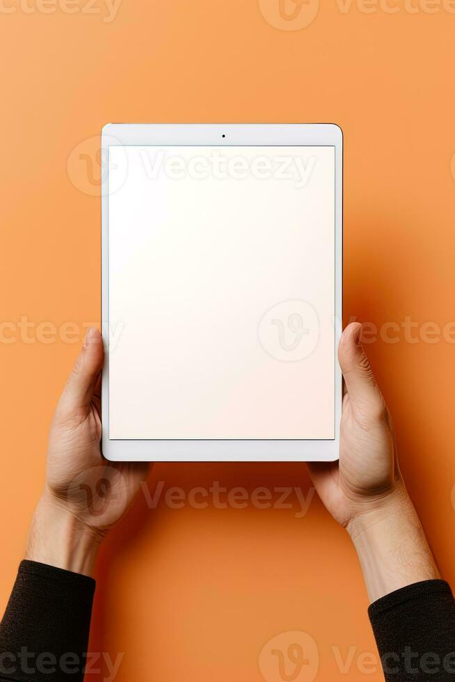 Hand holding tablet with mockup blank screen isolated on orange background. ai generated photo