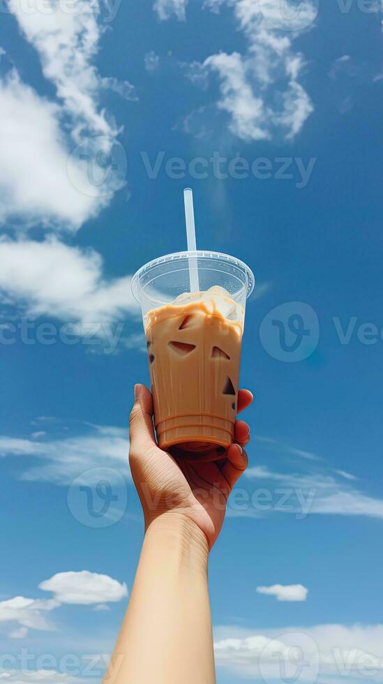 Hand holding iced coffee in a plastic cup with a blue sky and cloud background. ai generated photo