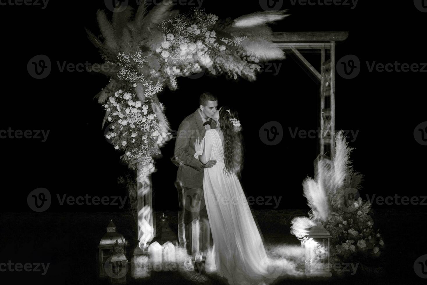 bride and groom against the backdrop of an evening wedding arch photo