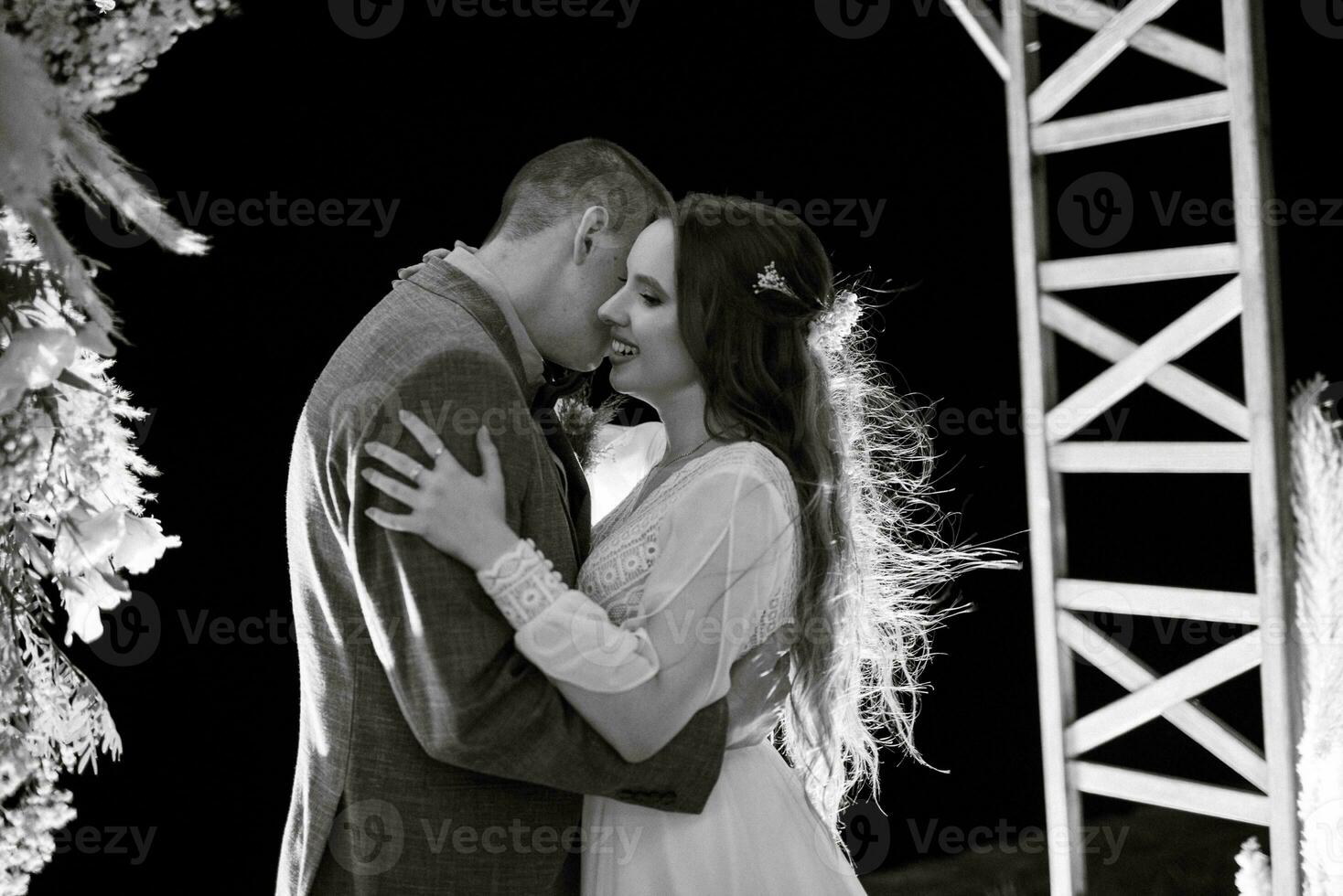 bride and groom against the backdrop of an evening wedding arch photo