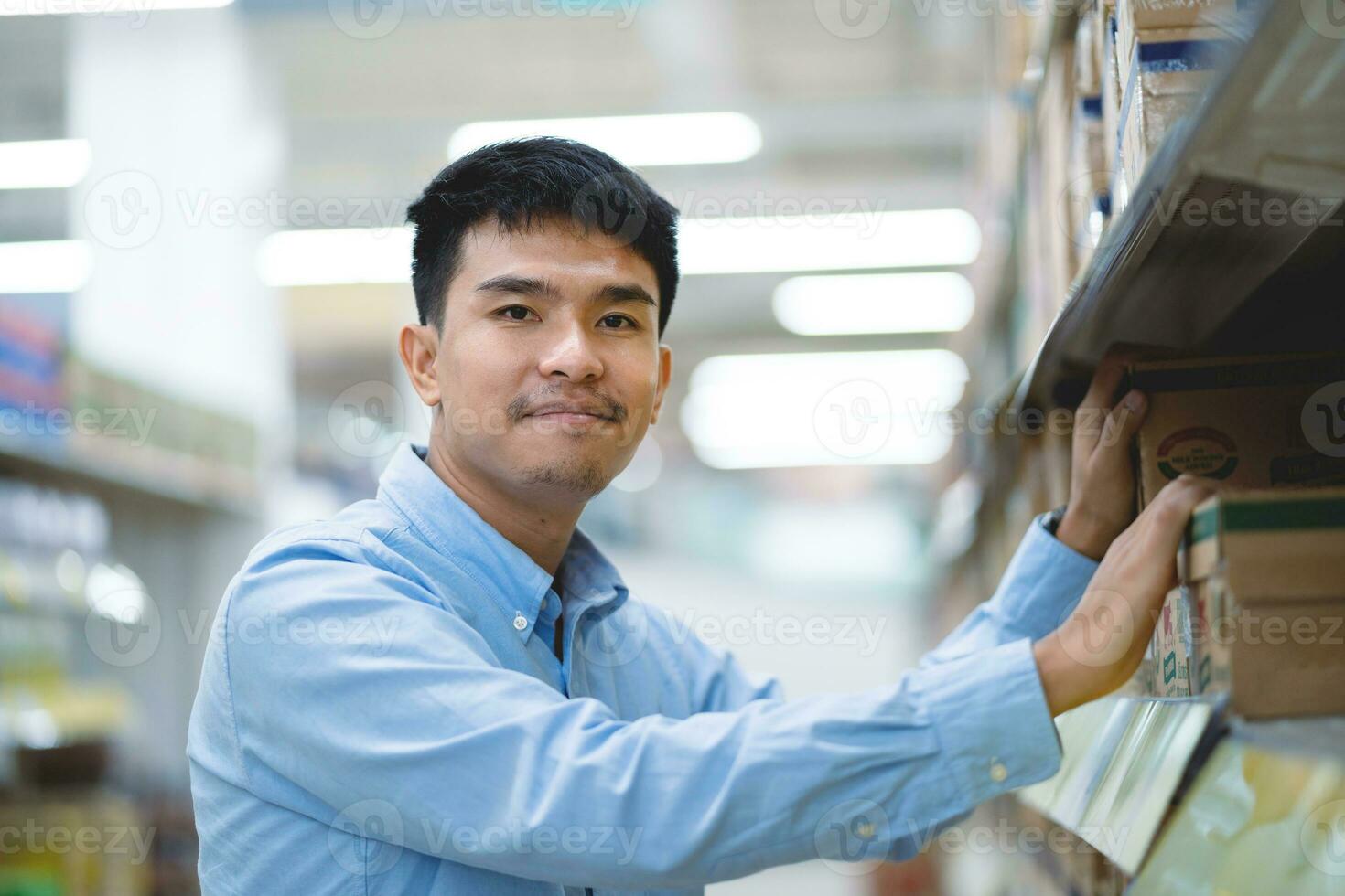 Asian male salesman, store manager, happy Asian manager smiling and looking at camera. Man selling groceries in a supermarket. photo