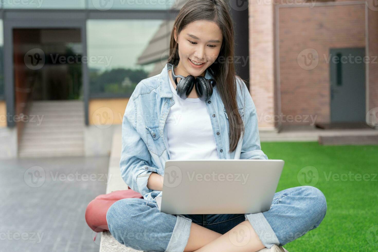 Beautiful Asian woman female student excited checking language test results on laptop. Smile girl happy study online. book in college campus. Portrait female on international Asia University photo