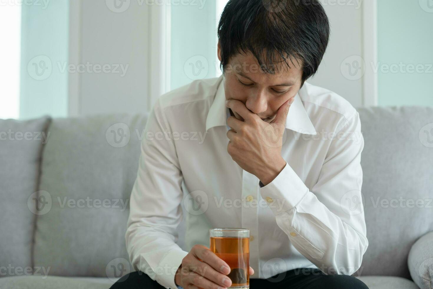 Depressed young business man addicted feeling bad drinking whiskey alone at home, stressed frustrated lonely drinking alcohol suffers from problematic liquor, alcoholism, life and family problems photo