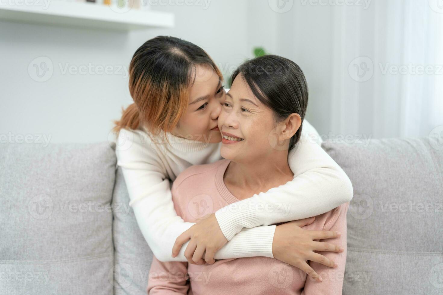 madre día, linda asiático adolescente niña abrazando y besos en el mejilla, maduro medio años mamá. amar, beso, cuidado, contento sonrisa disfrutar familia tiempo. celebrar especial ocasión, contento cumpleaños, alegre Navidad. foto