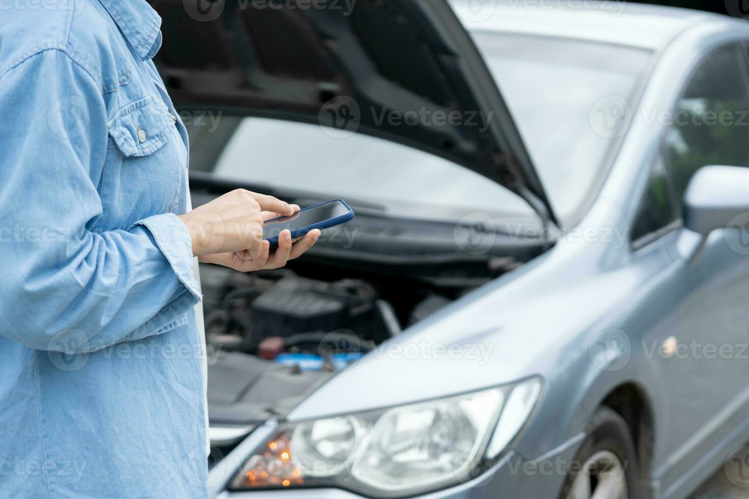 breakdown, broken car, repair. Woman uses mobile phone check insurance premiums through application due to car accident . Find garage to get car fixed during country tour, waiting for help, emergency. photo