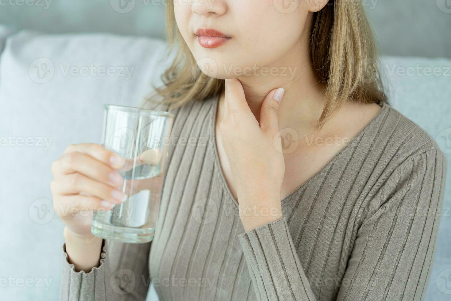 Asian woman put her hand on her neck due to a sore throat. female tonsillitis causes a inflammation. treated by taking water, taking antibiotics, consult a doctor, virus, corona virus, Influenza, flu photo