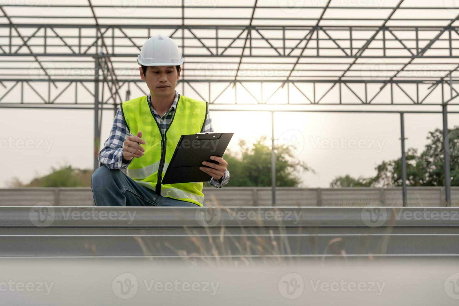 inspector or engineer is inspecting construction and quality assurance new factory using a checklist. Engineers or architects or contactor work to build the factory before handing it over to the home photo