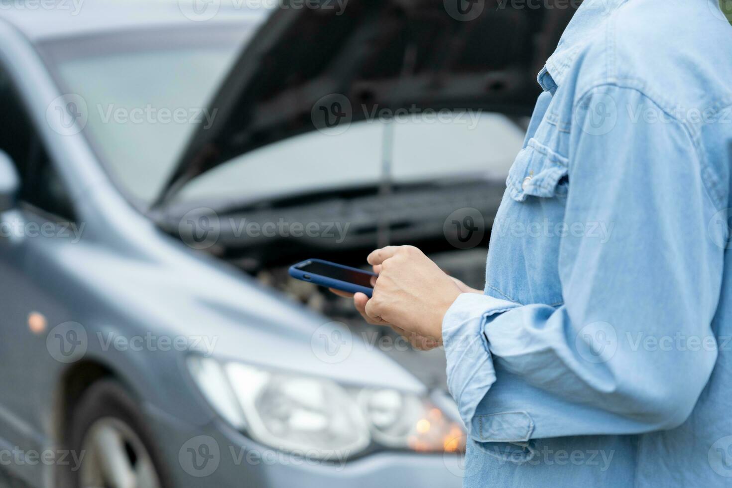 breakdown, broken car, repair. Woman uses mobile phone check insurance premiums through application due to car accident . Find garage to get car fixed during country tour, waiting for help, emergency. photo