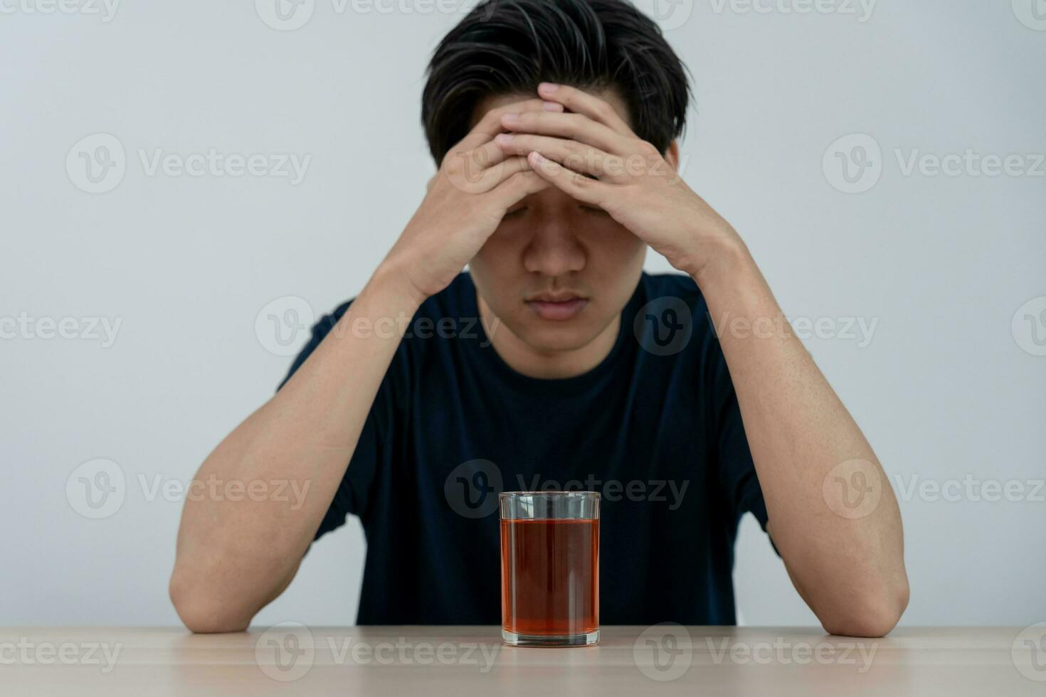 Depressed young Asian man addicted feeling bad drinking whiskey alone at home, stressed frustrated lonely drinking alcohol suffers from problematic liquor, alcoholism, life and family problems photo