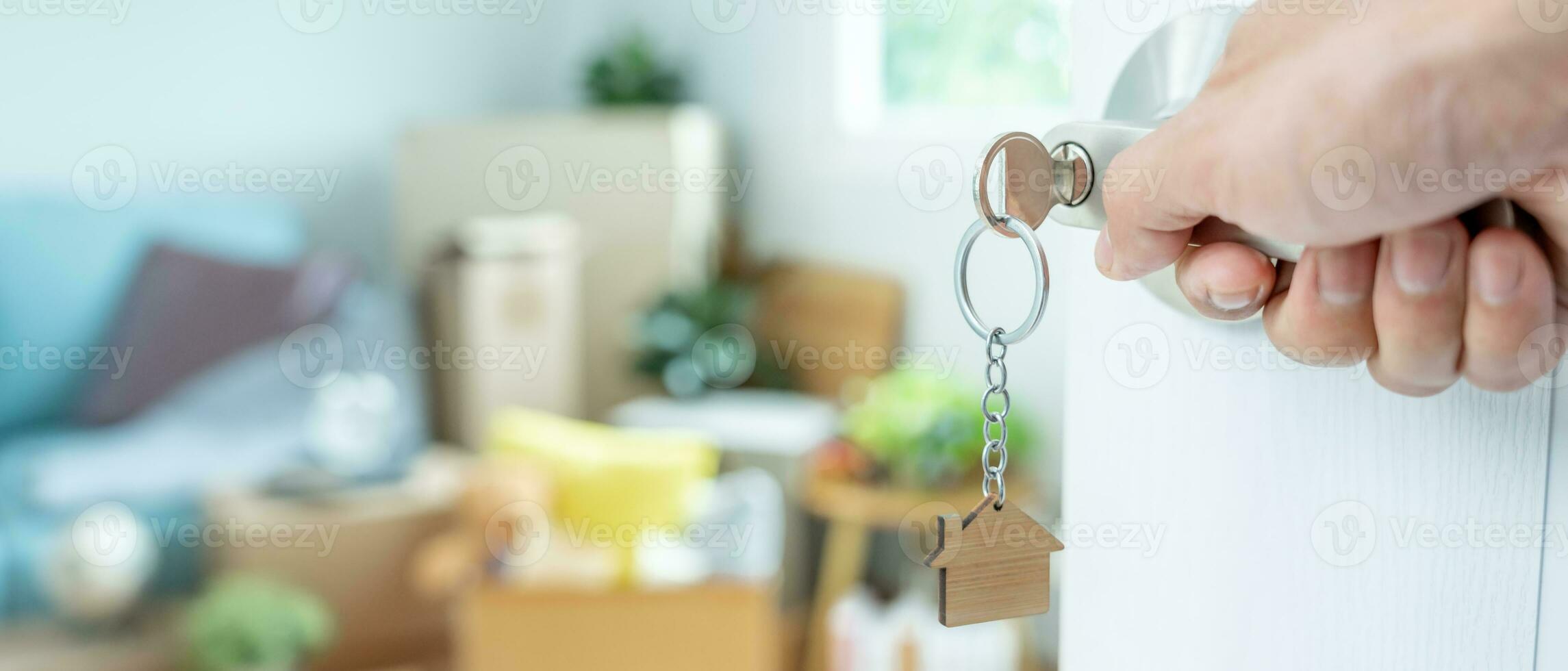 Moving house, relocation. The key was inserted into the door of the new house, inside the room was a cardboard box containing personal belongings and furniture. move in the apartment, banner photo