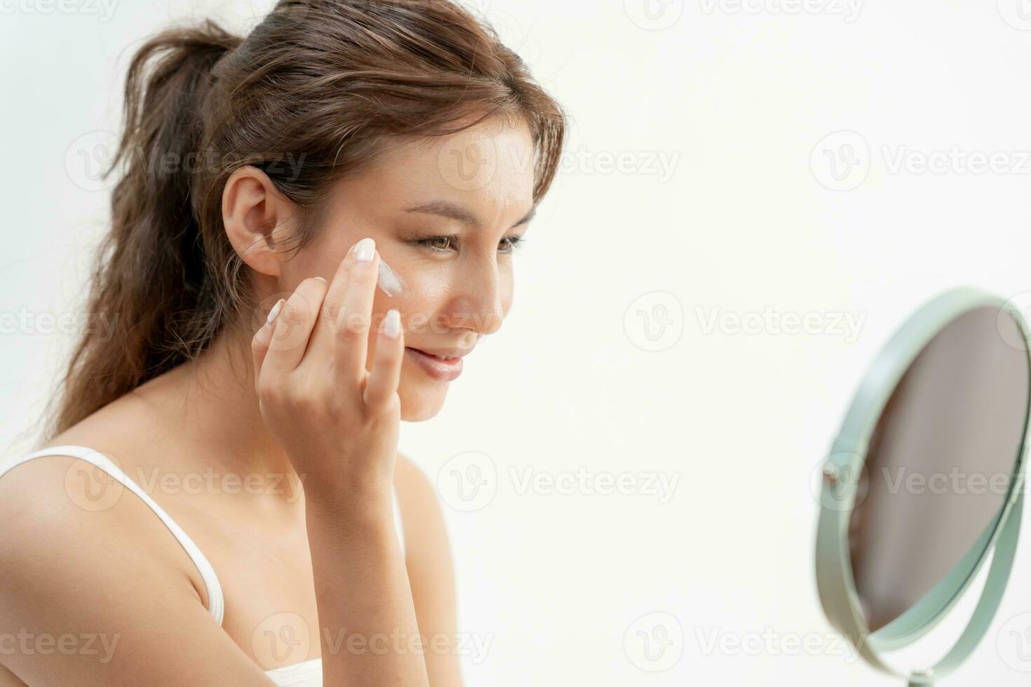 Beautiful woman sit in front of a mirror. face of a healthy woman applying cream and makeup. Advertisement for skin cream, anti-wrinkle, baby face, whitening, moisturizer, tighten pores serum photo