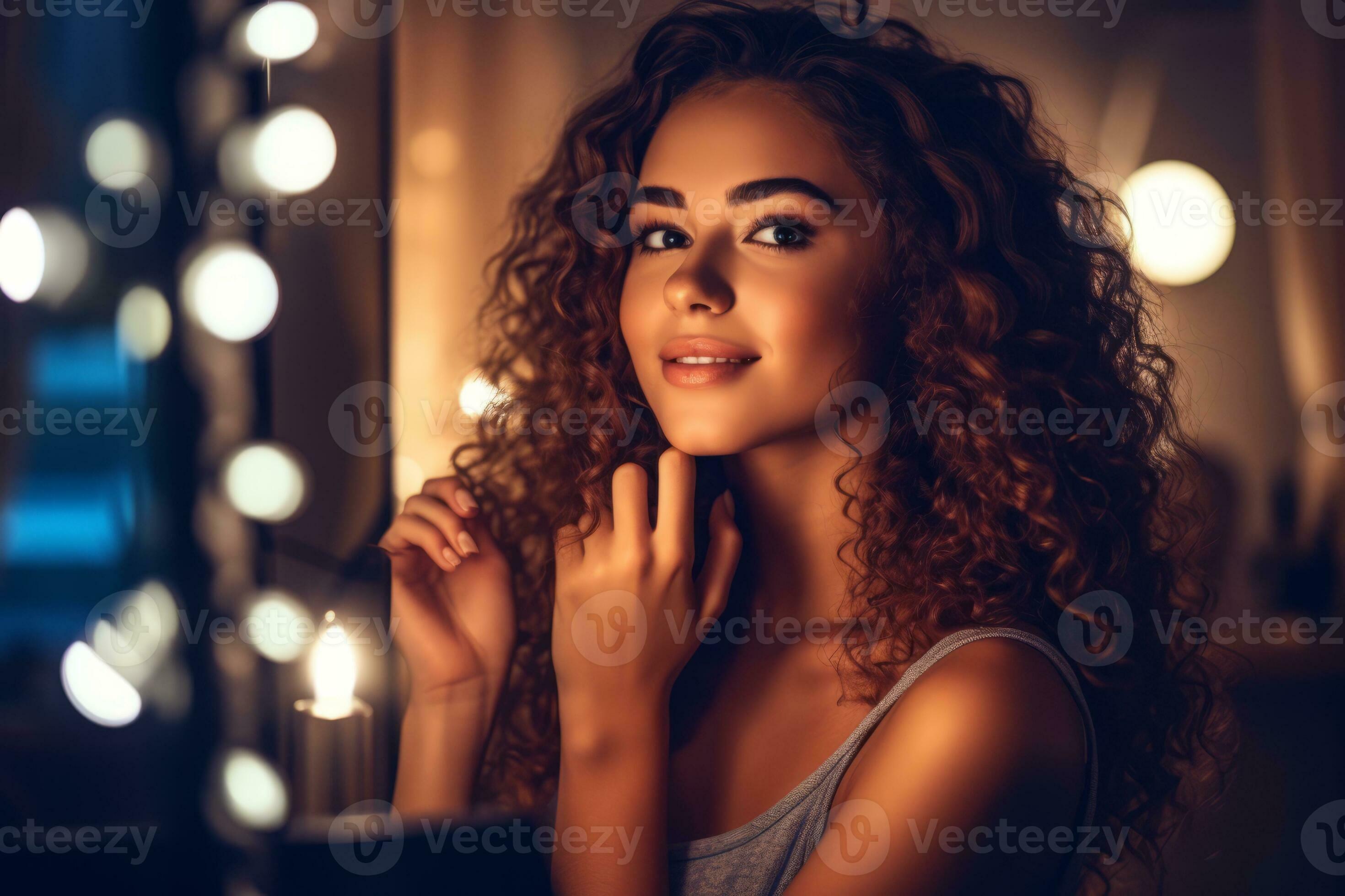 A young woman applying makeup in front of a well-lit vanity mirror