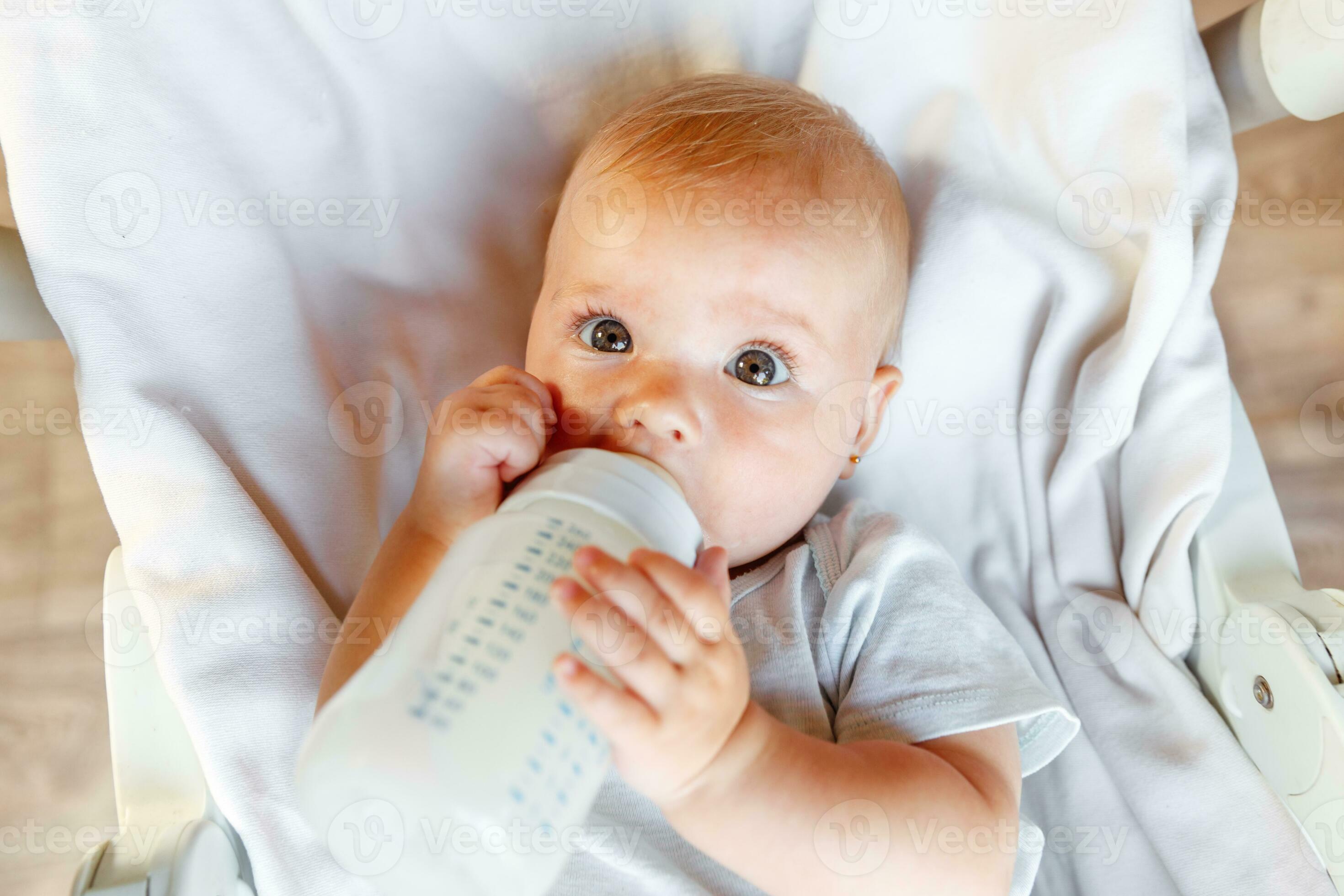 A two year old toddler drinking a bottle of baby milk, while sitting,  lying, on a settee playing on her iPad Stock Photo - Alamy