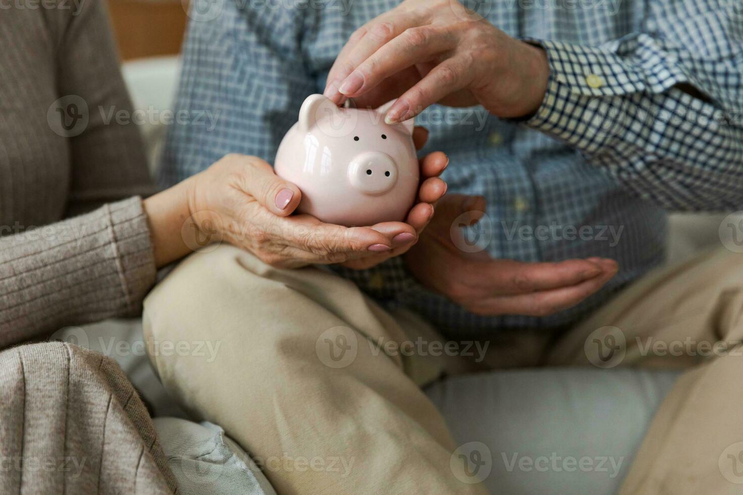 Saving money investment for future. Senior adult mature couple hands putting money coin in piggy bank. Old man woman counting saving money planning retirement budget Saving investment banking concept photo
