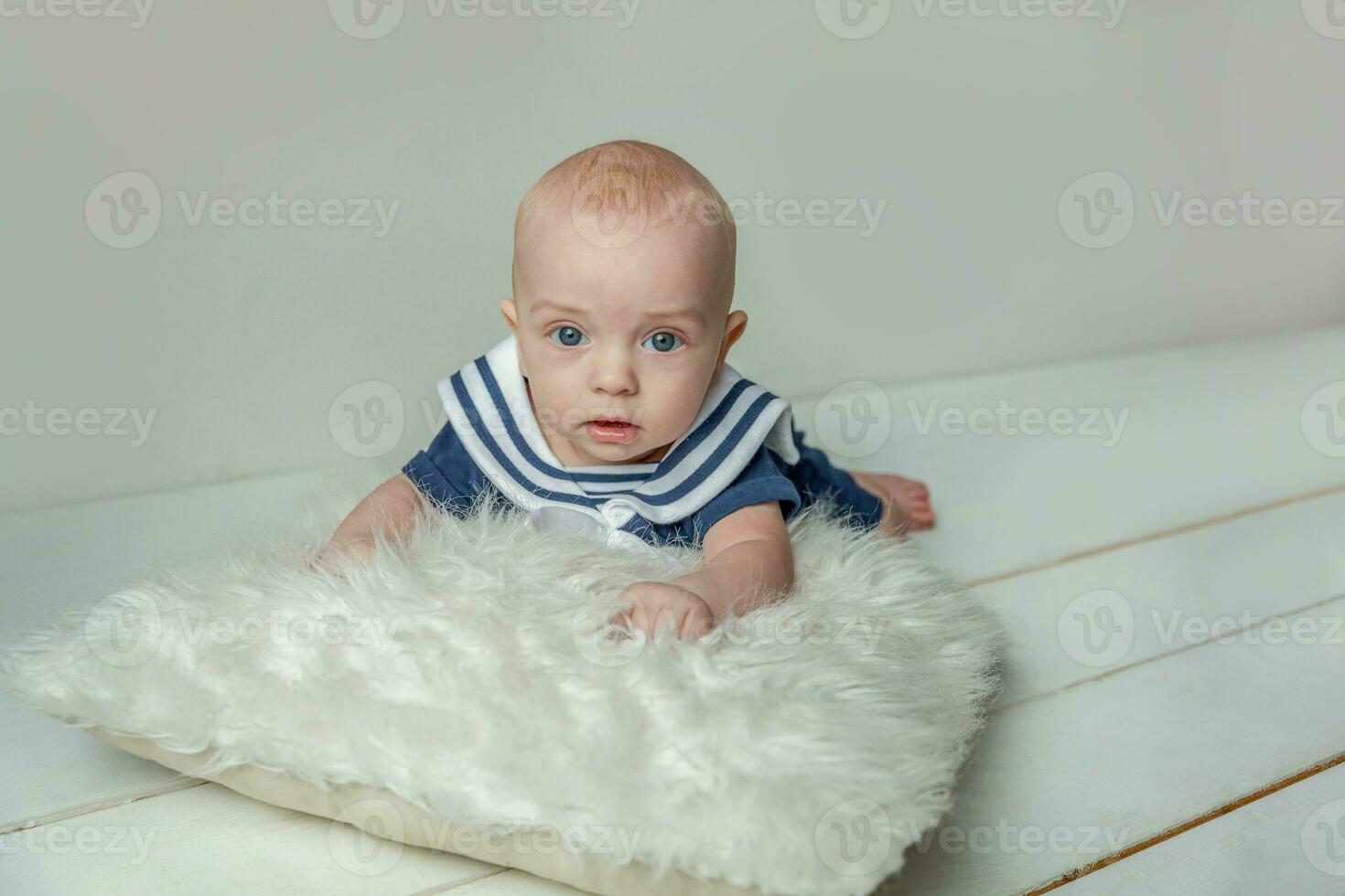 Infant baby boy lies on pillow on white bedroom background photo