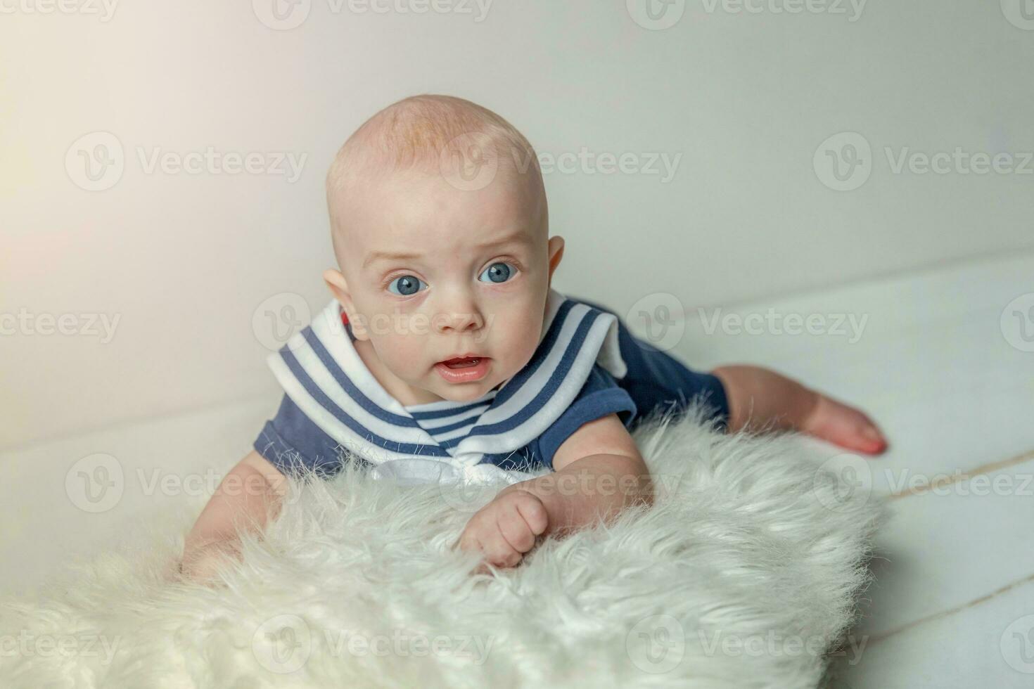 Infant baby boy lies on pillow on white bedroom background photo