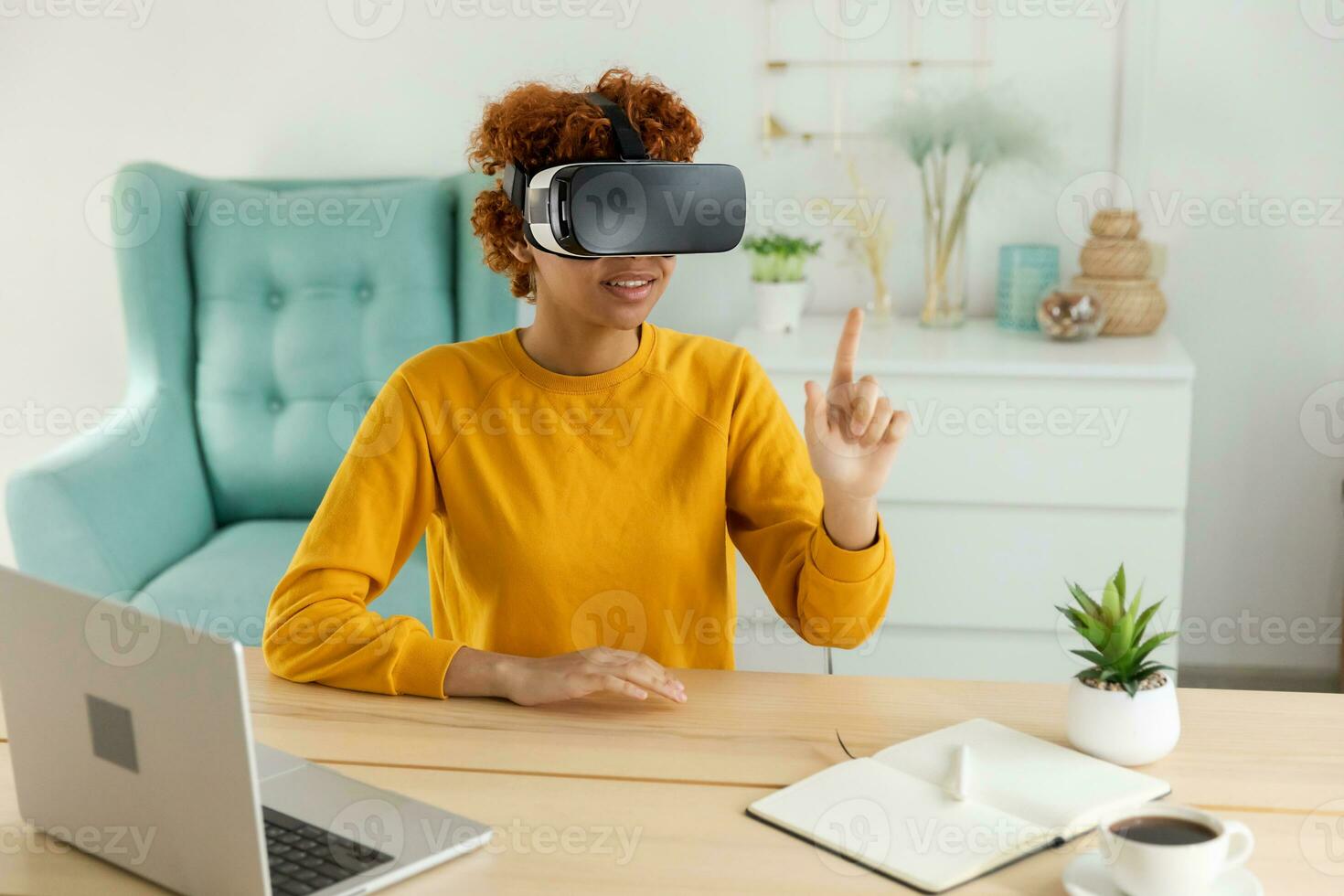 African american young woman wearing using virtual reality metaverse VR glasses headset at home. Girl touching air during VR experience on virtual reality helmet. Simulation hi-tech videogame concept. photo