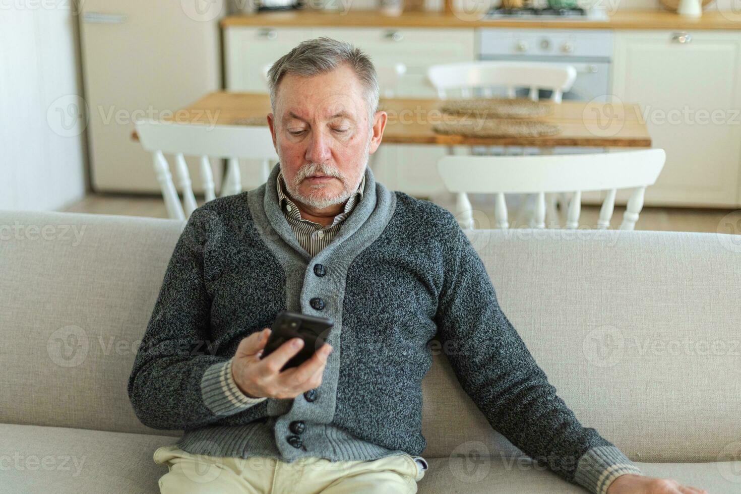 Happy middle aged senior man holding using smartphone touch screen typing scroll page. Stylish older mature beard grandfather with cell phone using internet social media apps at home. Shopping online. photo