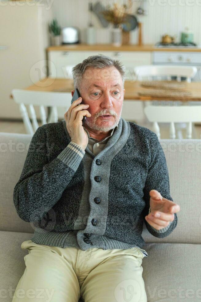 Happy middle aged senior man talking on smartphone with family friends. Older mature grandfather with cell phone talking with grown up children, resting at home. Older generation modern tech usage. photo
