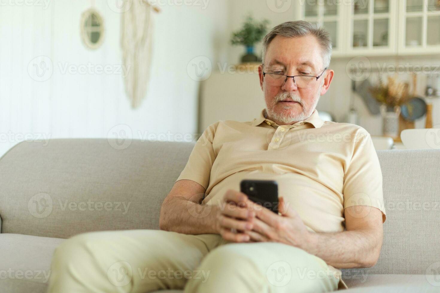 Happy middle aged senior man holding using smartphone touch screen typing scroll page. Stylish older mature beard grandfather with cell phone using internet social media apps at home. Shopping online. photo