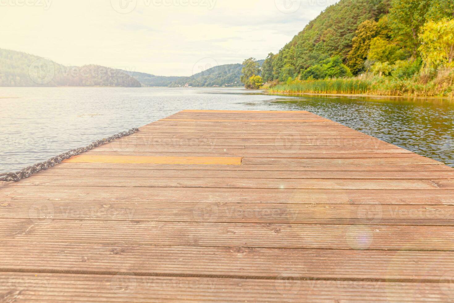 Fishing tourism relax concept. Beautiful forest lake or river on sunny summer day and old rustic wooden dock or pier. Fishing bridge on morning lake. photo