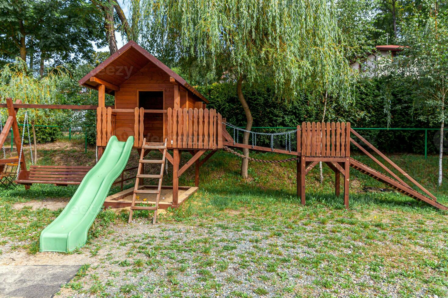 Empty modern wooden children playground set on green yard in public park in summer day. Funny toy land for kids. Urban exercise activities for child outdoors. Neighborhood childhood concept. photo